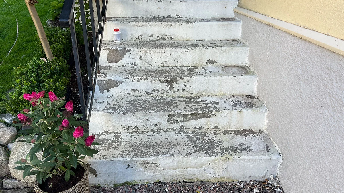 Färgflagad äldre betongtrappa med ytskador och åldrad porös betong.